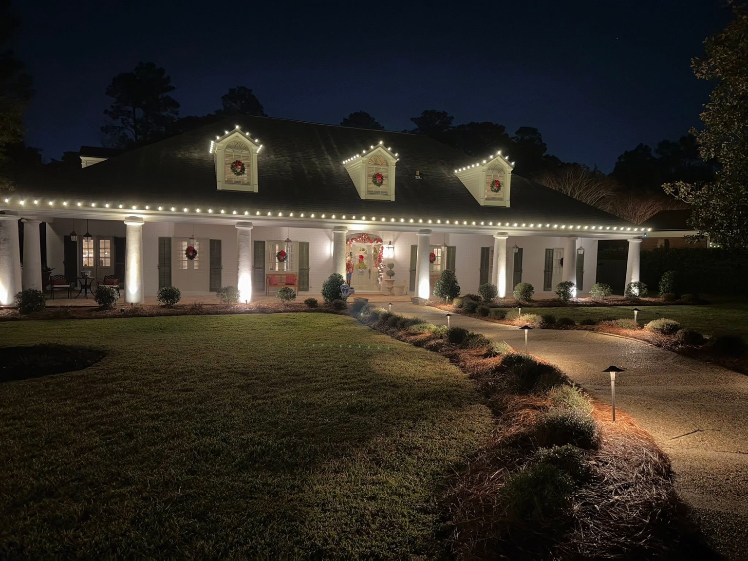 Warm white Christmas lights outlining a classic home's long roofline and dormers