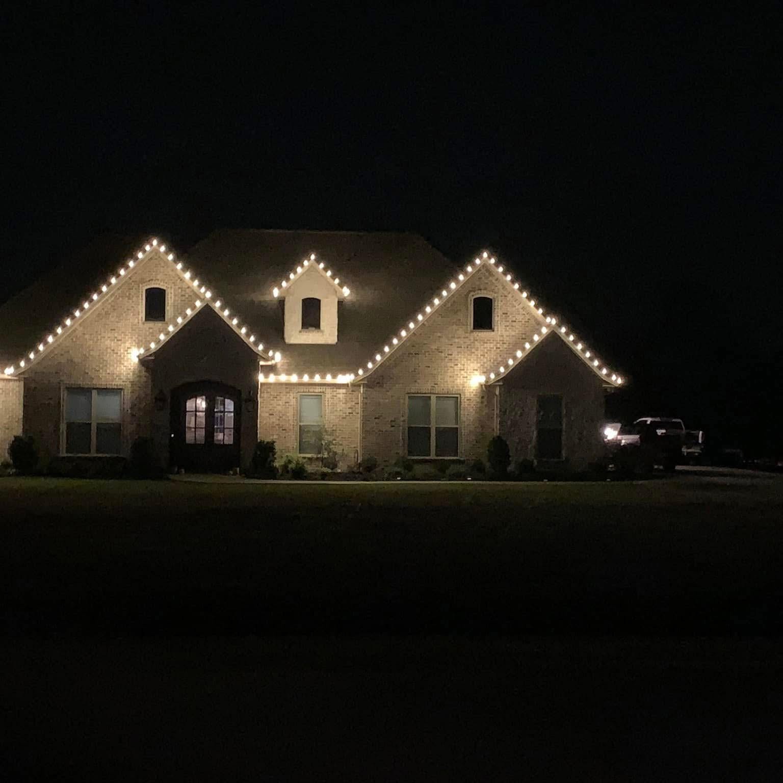 Warm white Christmas lights outlining multiple brick home gables