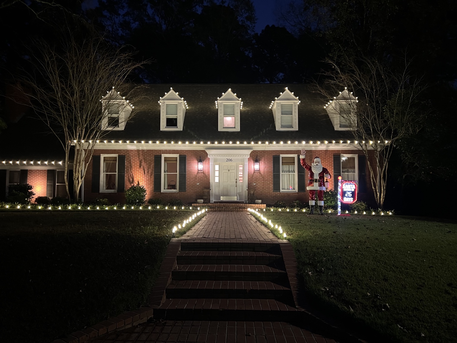 Warm white residential Christmas lights on rooflines, dormers, landscaping and walkway